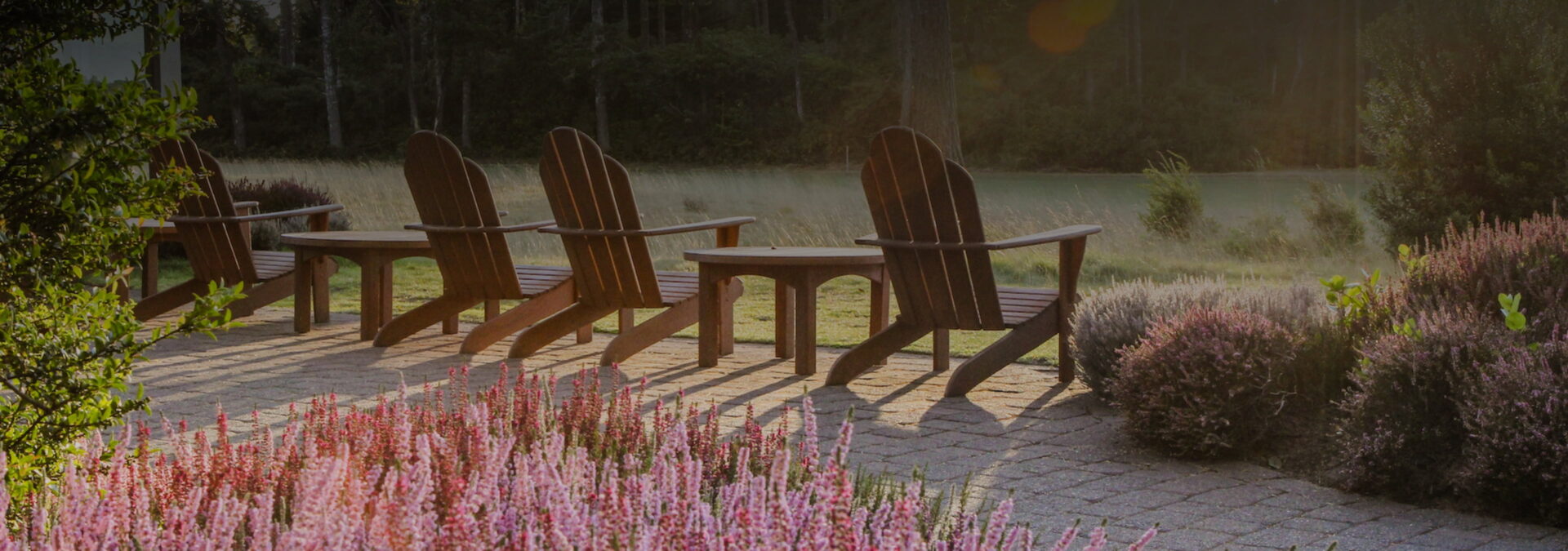 Adirondack chairs on a deck looking over a green field