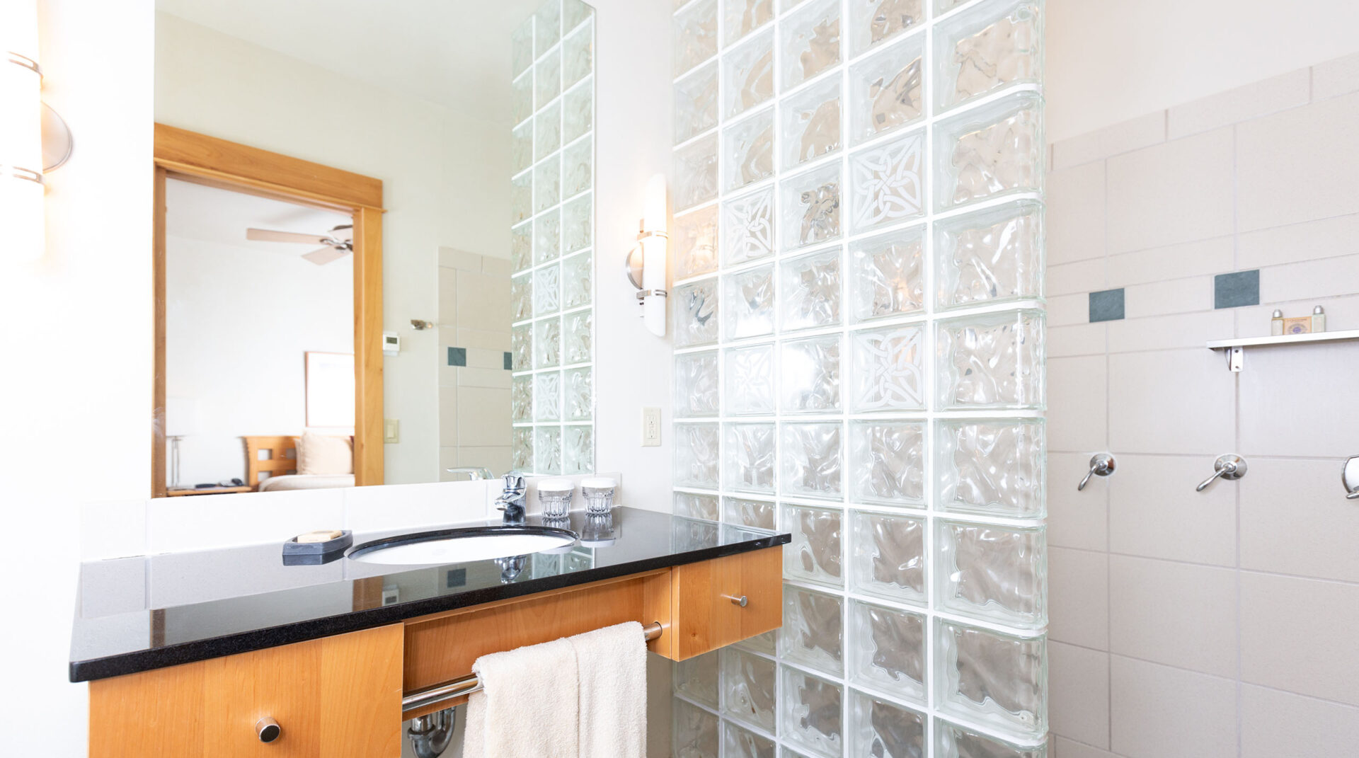 A bathroom at a cabin in The Grove with a glass block shower and black marble countertops