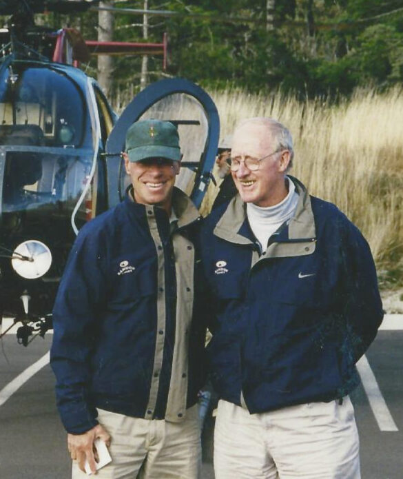 Two men hugging in front of a helicopter