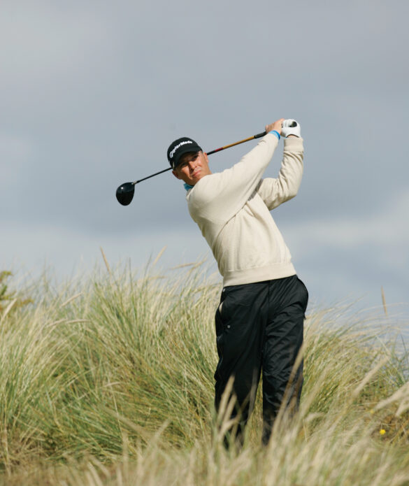 Golfer hitting ball in tall grass